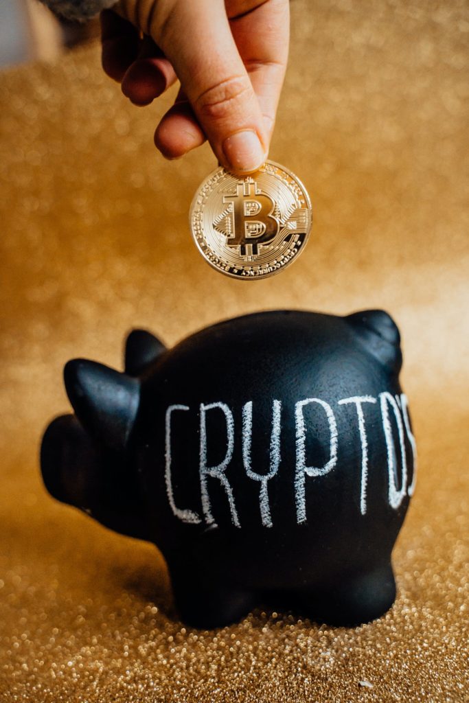 A  piggy bank with someone putting crypto coin in it. Representing Blockchain Wallet.